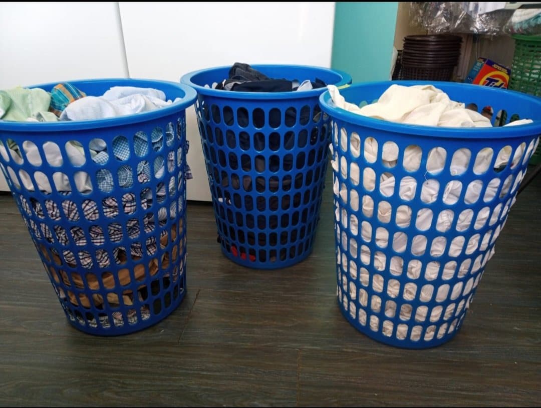 Tres hampers azules de Lavanderia Klin llenos de ropa suelta